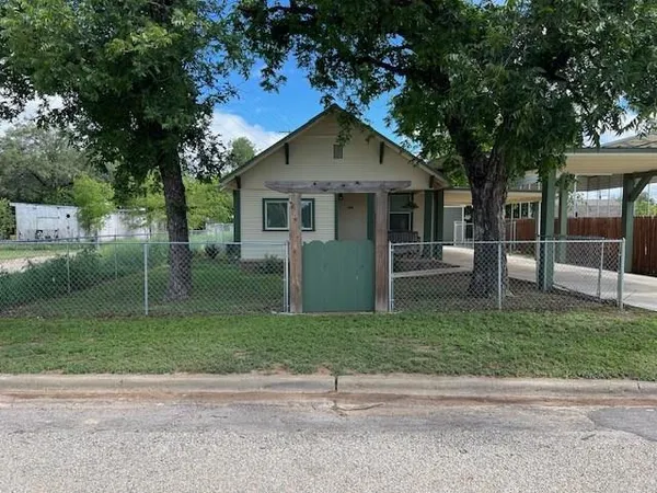 a front view of a house with a yard and trees