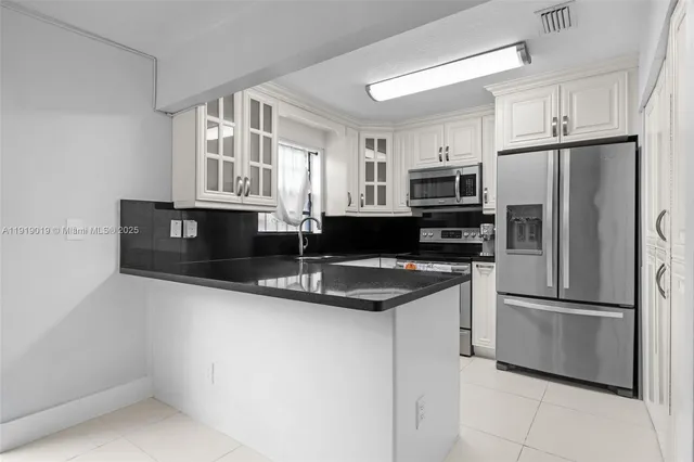 a kitchen with granite countertop a sink stainless steel appliances and cabinets