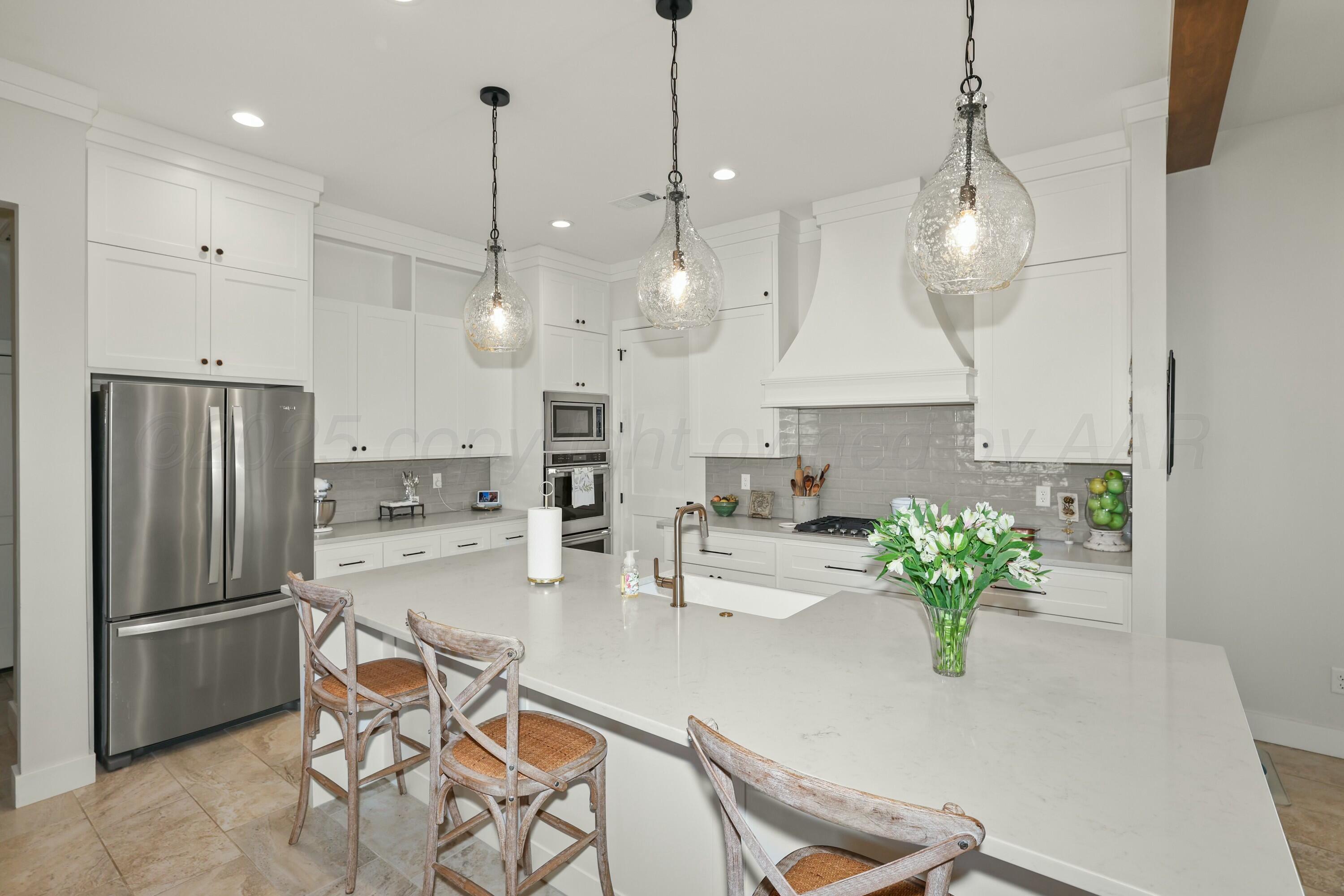 19081 Elk Springs Road Amarillo, TX 79119 - Photo 13 of 41 a kitchen with stainless steel appliances granite countertop a refrigerator a sink a stove a chandelier a dining table and chairs