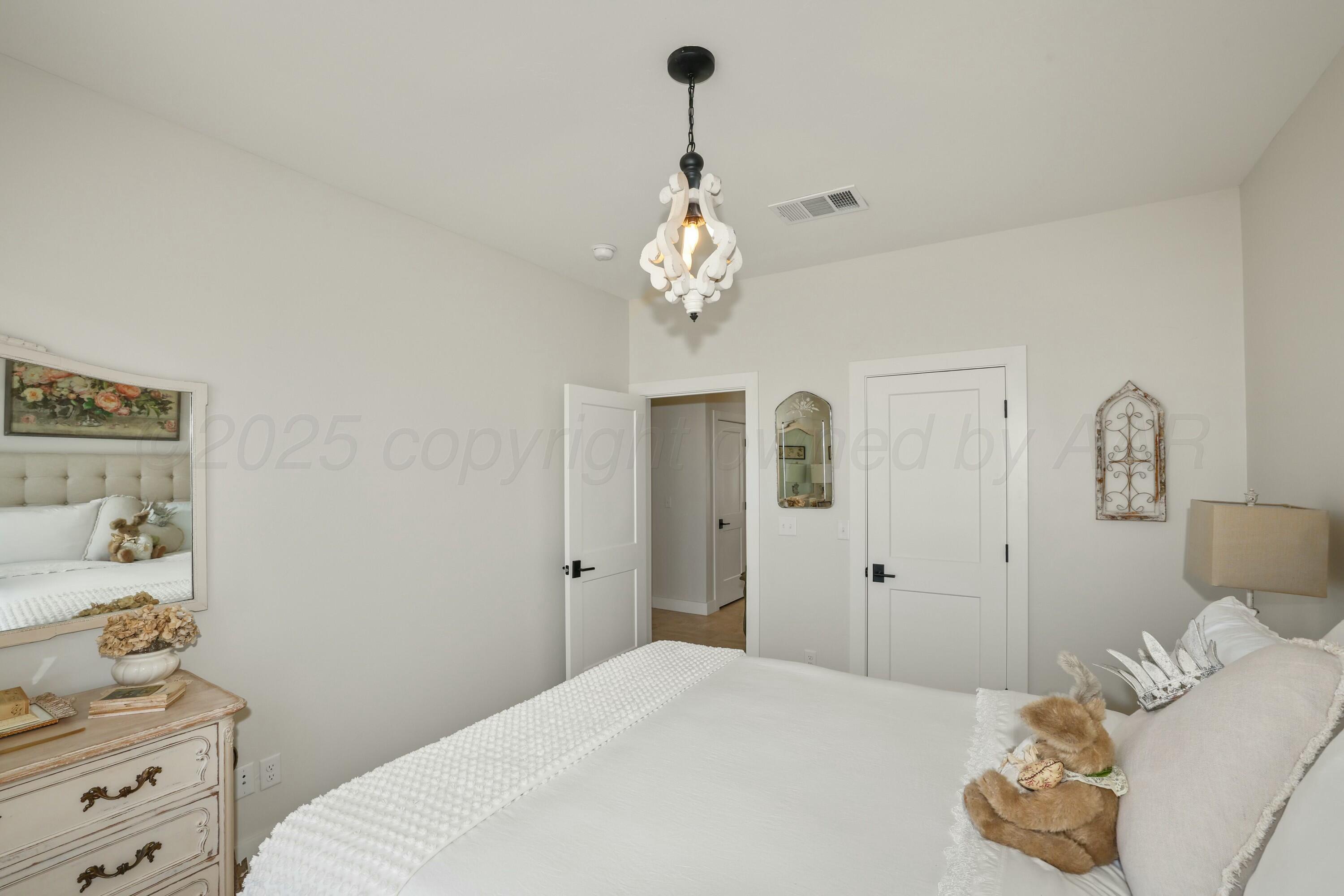 19081 Elk Springs Road Amarillo, TX 79119 - Photo 30 of 41 a bedroom with a bed and a chandelier