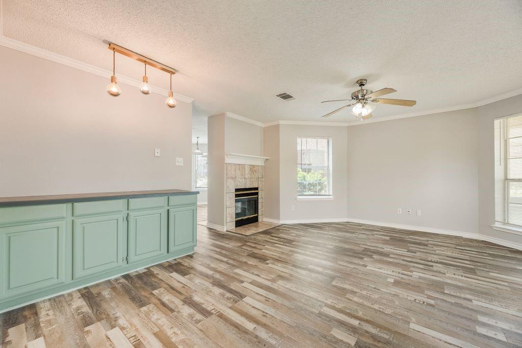 5610 Eagle Rock Road Arlington, TX 76017 - Photo 6 of 33 Open-concept living area featuring wood-finish flooring, a tiled fireplace with mantel, and multiple windows