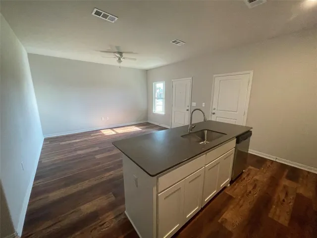a room with kitchen island a sink and wooden floor