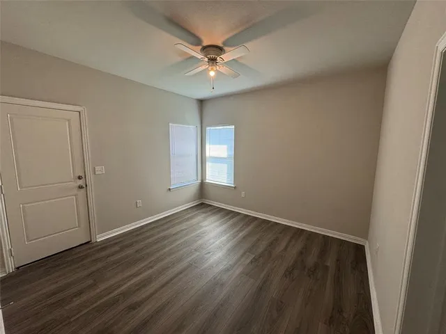 an empty room with wooden floor and fan