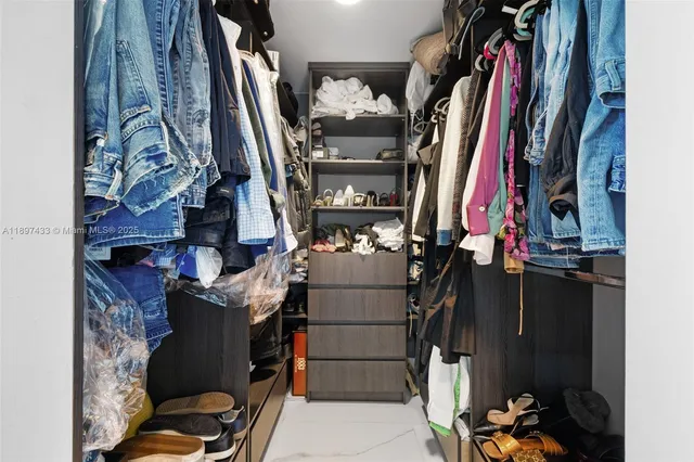 a view of walk in closet with clothes and shoes