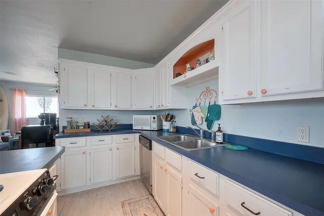 a kitchen with stainless steel appliances granite countertop a sink a stove and white cabinets