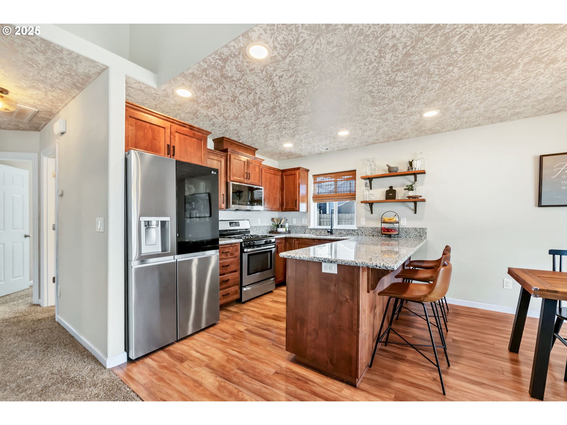 525 12th Street Aumsville, OR 97325 - Photo 5 of 23 a open kitchen with stainless steel appliances granite countertop a refrigerator a stove top oven and a sink with wooden floor