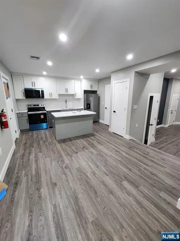 a large kitchen with stainless steel appliances wooden floors and wooden cabinets