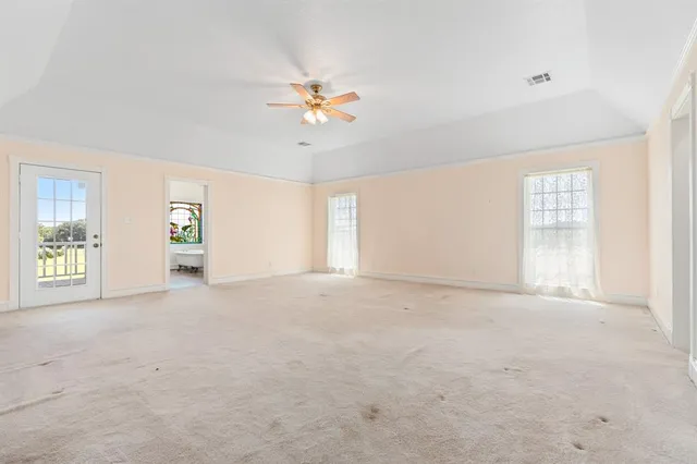 an empty room with windows and chandelier fan