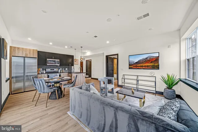 a living room with furniture kitchen view and a potted plant