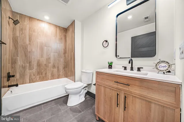 a bathroom with a double vanity sink toilet mirror and bathtub