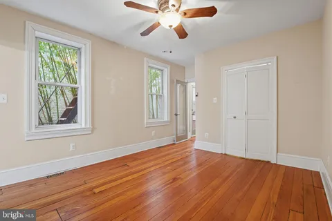 a view of empty room with wooden floor and fan