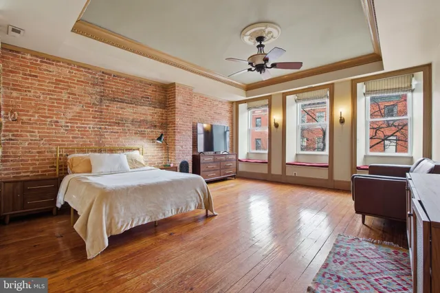 a spacious bedroom with a bed and wooden floor