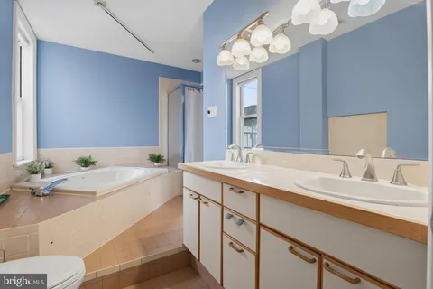 a bathroom with a granite countertop sink a large mirror and a bathtub