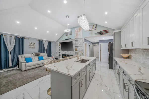 a view of living room kitchen with stainless steel appliances granite countertop couches and a flat screen tv