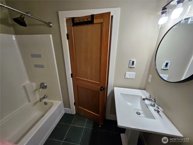 a bathroom with a tub a sink and a mirror