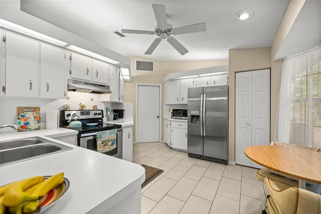 a kitchen with stainless steel appliances granite countertop a sink a stove a refrigerator cabinets and chairs
