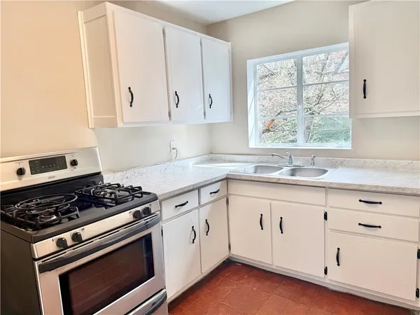 a white kitchen with sink and window