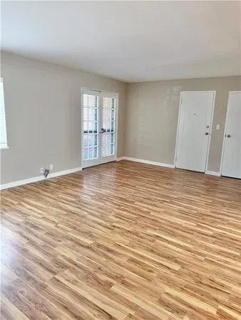 a view of an empty room with wooden floor and a window