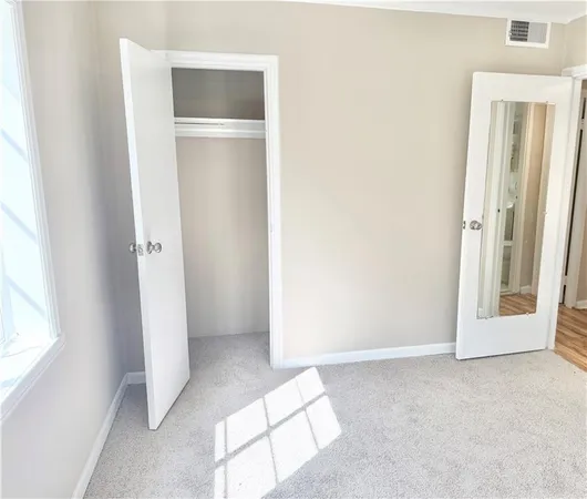 a view of an empty room with closet and a window