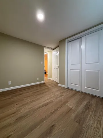 a view of an empty room with wooden floor and closet