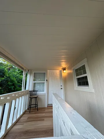 a view of a hallway with wooden floor and staircase