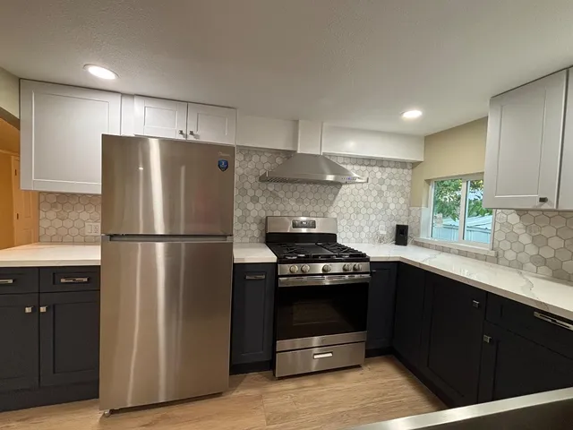 a kitchen with stainless steel appliances granite countertop a refrigerator a sink dishwasher a stove and white cabinets