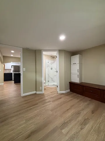 a view of an empty room with wooden floor and windows