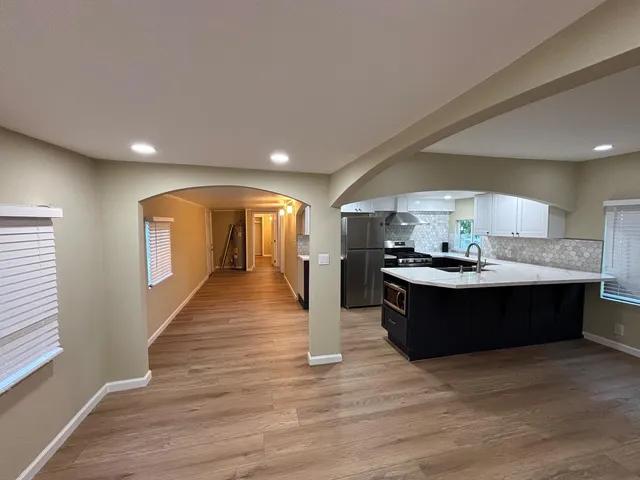 a living room with wooden floor and kitchen view