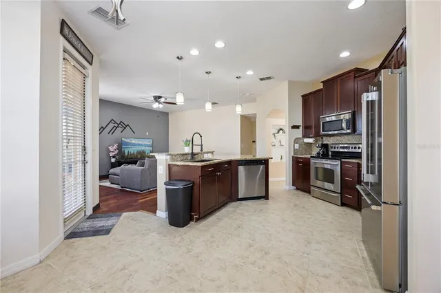 a kitchen with stainless steel appliances granite countertop a dining table chairs stove refrigerator and cabinets