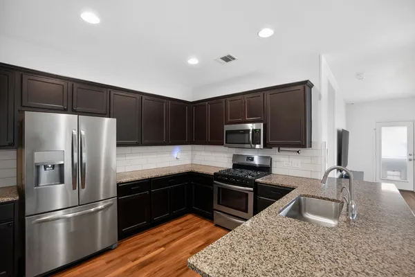 a kitchen with granite countertop a refrigerator stove and microwave