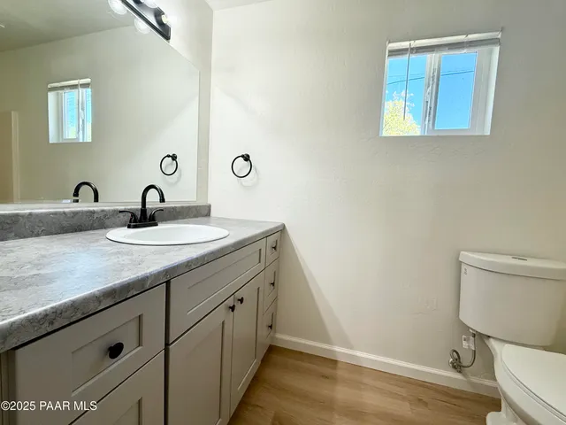 a bathroom with a granite countertop sink a toilet and a mirror