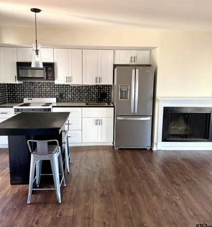 a kitchen with kitchen island a white counter top space wooden floor and a fireplace