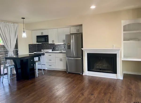 a kitchen with a refrigerator stove and wooden floor