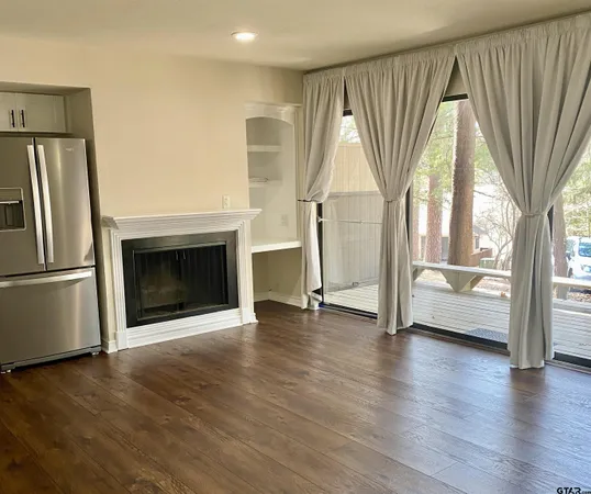 a view of empty room with wooden floor and fireplace