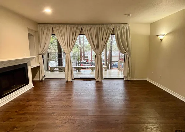 an empty room with wooden floor fireplace and windows