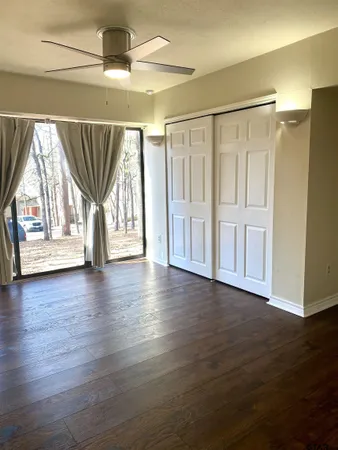a view of empty room with wooden floor and fan