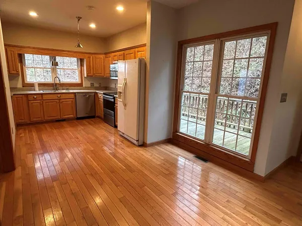 a view of a kitchen with a sink and dishwasher a refrigerator with wooden floor