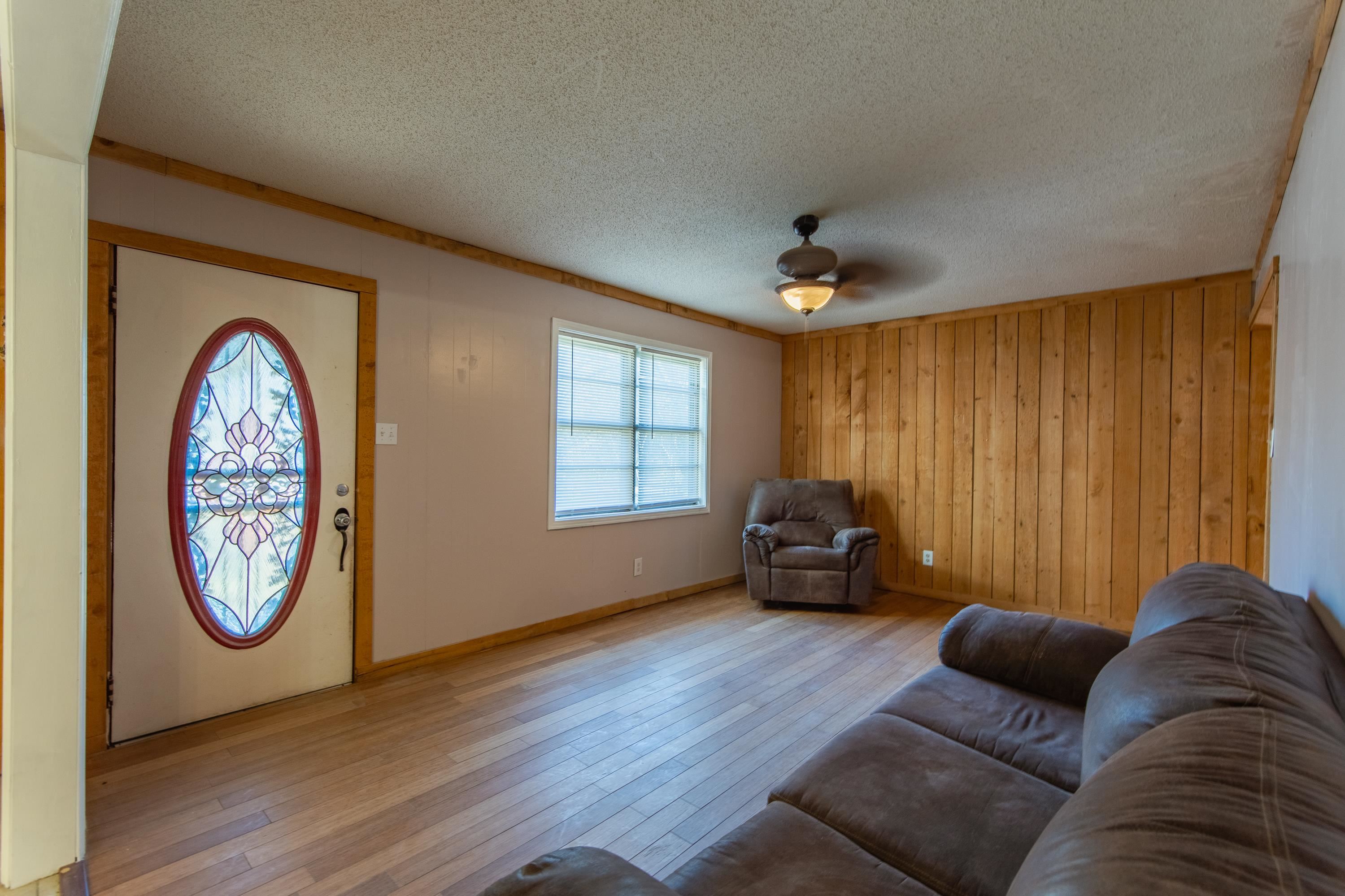 3001 Hamilton Road Ashland, MS 38603 - Photo 11 of 39 Living room with ceiling fan, light wood-type flooring, a textured ceiling, and wooden walls