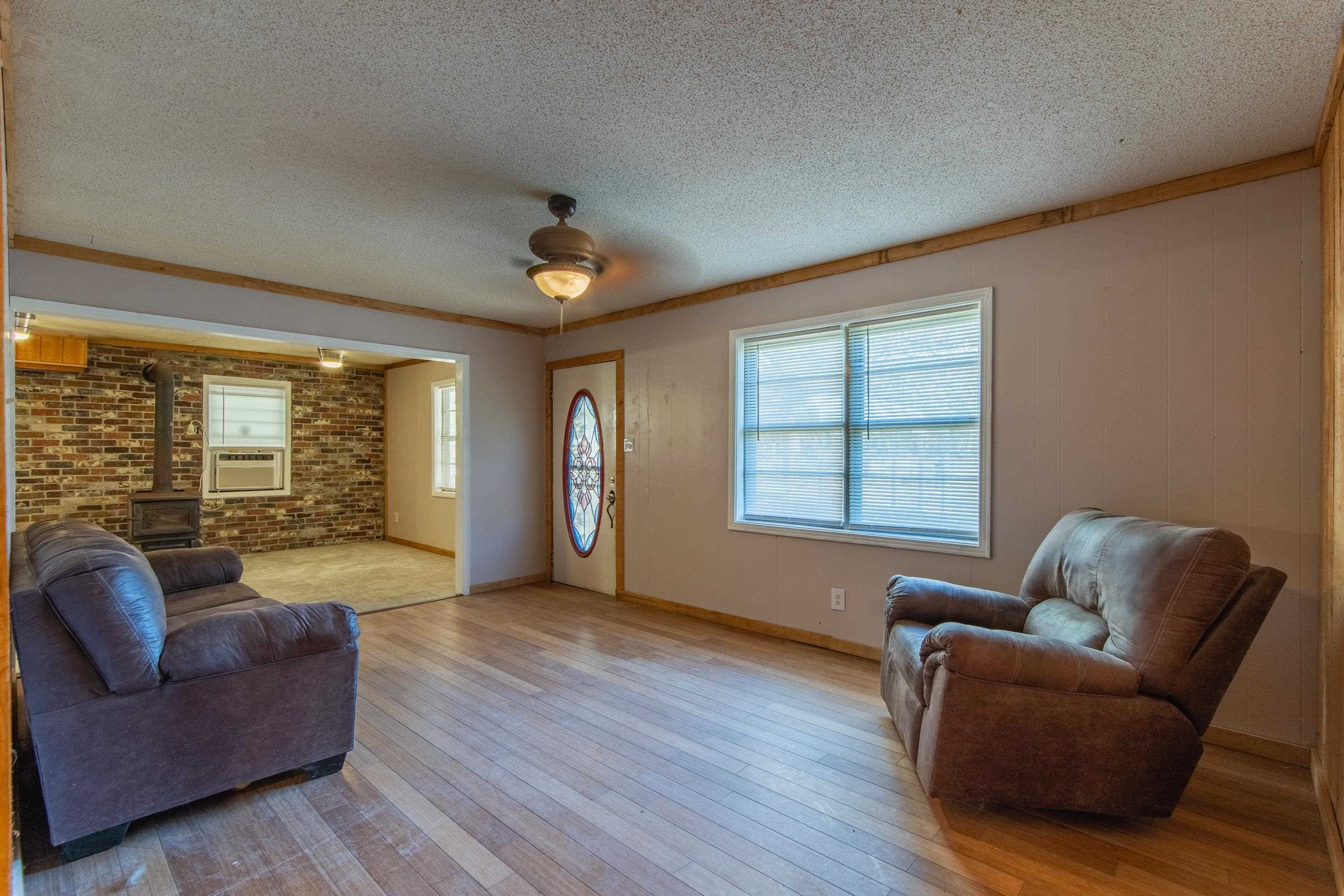 3001 Hamilton Road Ashland, MS 38603 - Photo 13 of 39 Living room featuring a wood stove, ceiling fan, ornamental molding, light hardwood / wood-style floors, and brick wall