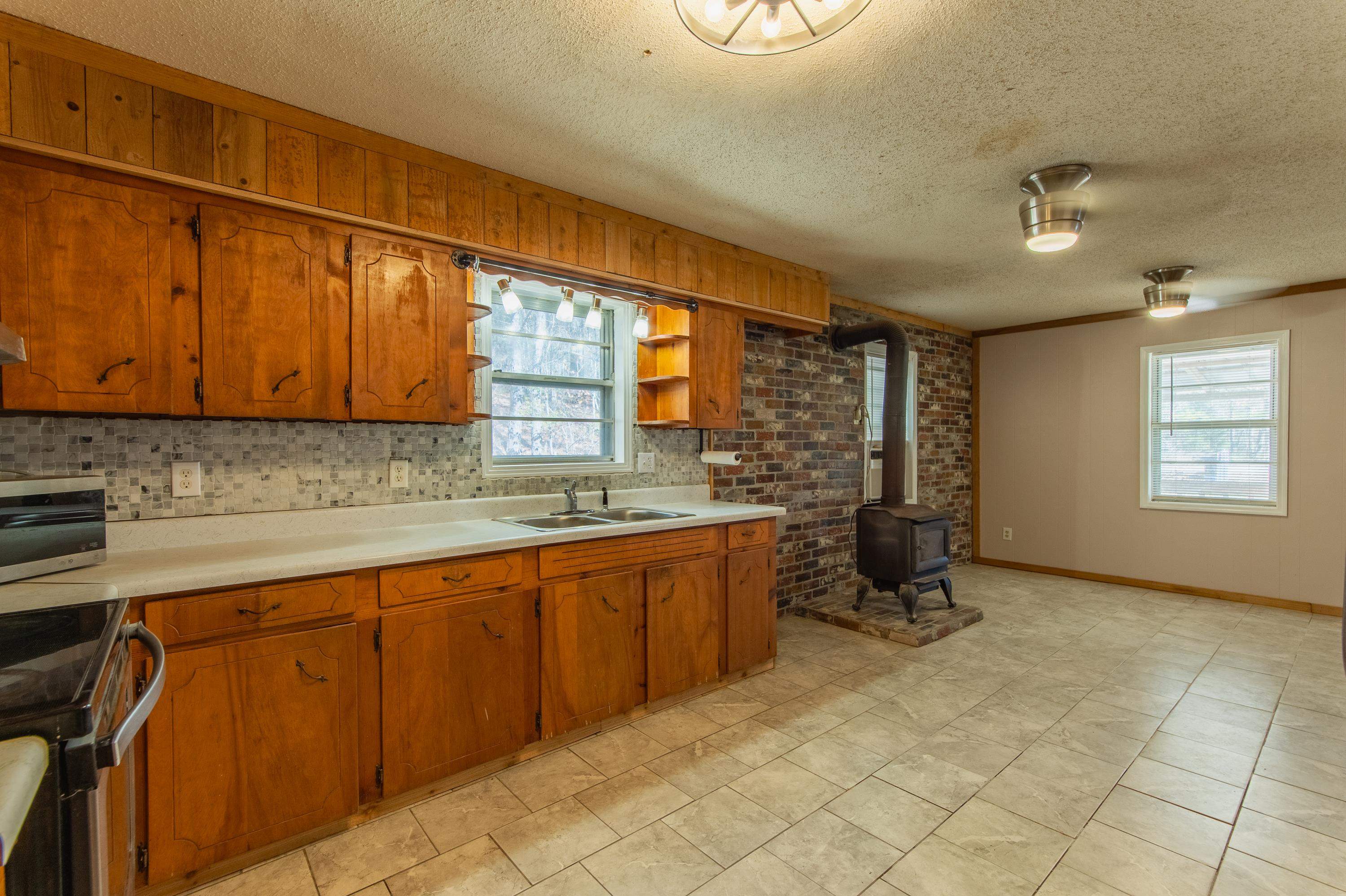 3001 Hamilton Road Ashland, MS 38603 - Photo 17 of 39 Kitchen featuring a wood stove, sink, stainless steel range oven, backsplash, and crown molding