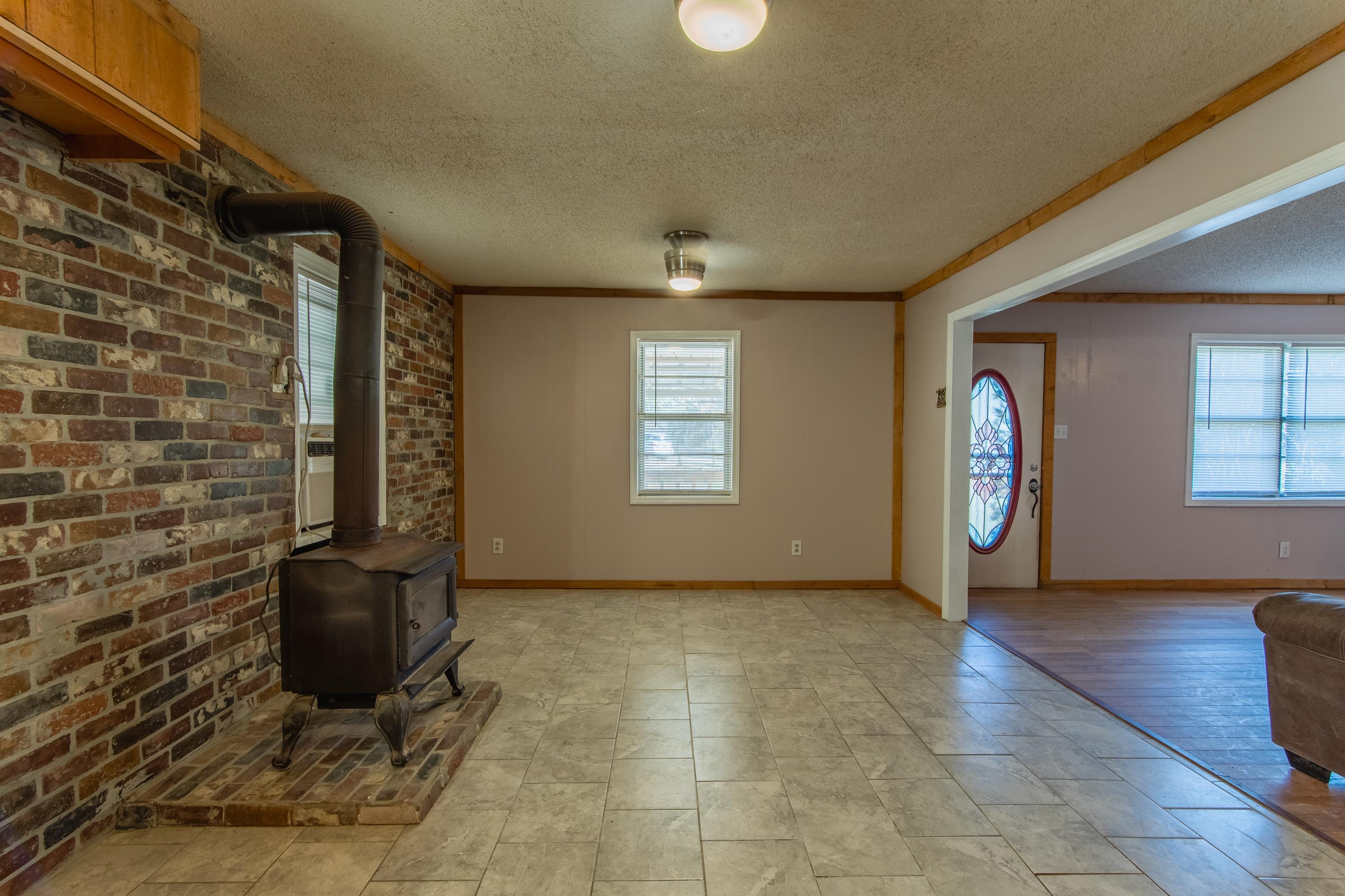 3001 Hamilton Road Ashland, MS 38603 - Photo 18 of 39 Unfurnished living room featuring plenty of natural light, a wood stove, and crown molding