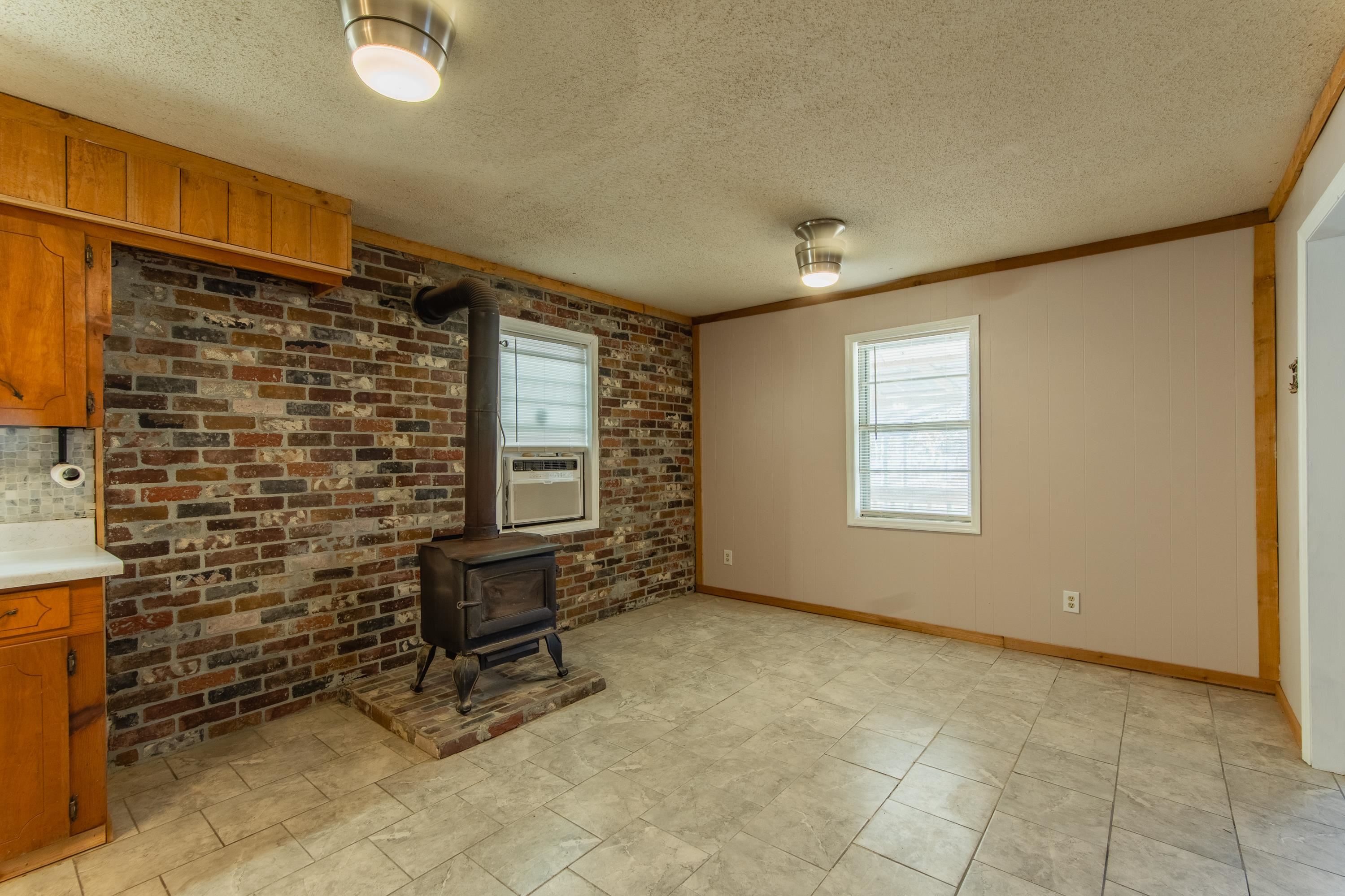 3001 Hamilton Road Ashland, MS 38603 - Photo 19 of 39 Unfurnished living room featuring a textured ceiling, a wood stove, and ornamental molding