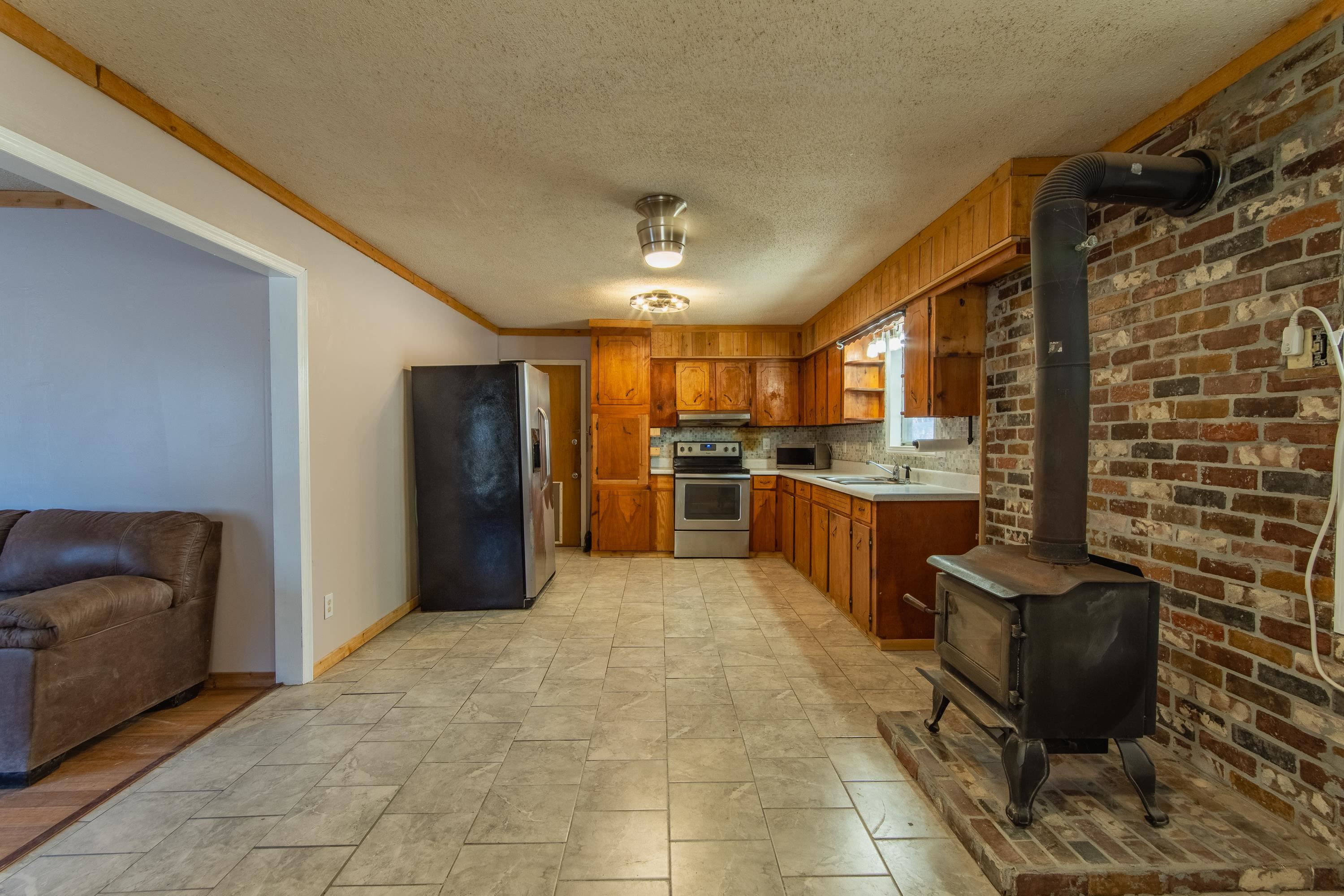 3001 Hamilton Road Ashland, MS 38603 - Photo 22 of 39 Kitchen with appliances with stainless steel finishes, backsplash, ornamental molding, a textured ceiling, and a wood stove