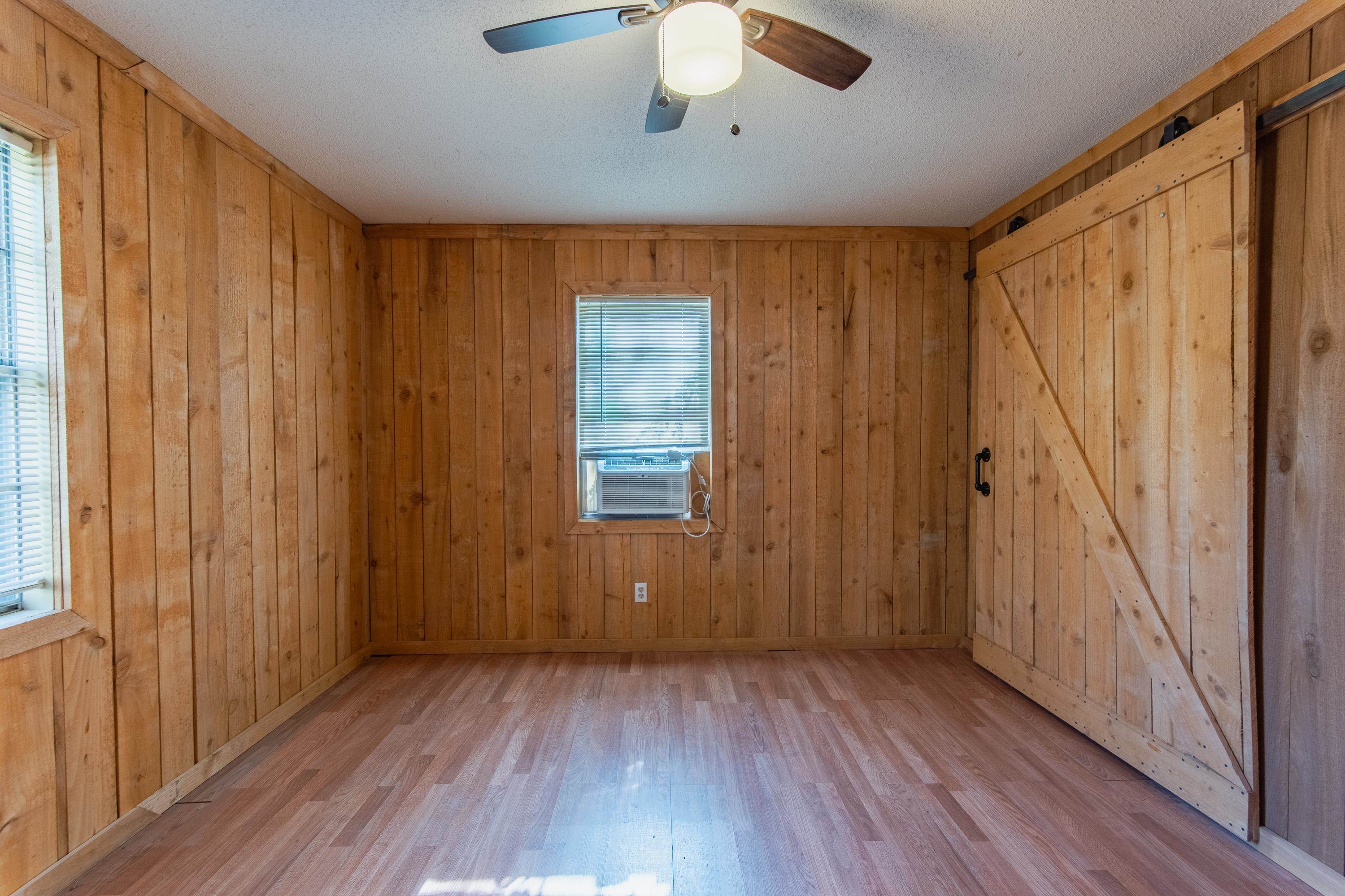 3001 Hamilton Road Ashland, MS 38603 - Photo 4 of 39 Spare room featuring wooden walls, a healthy amount of sunlight, and light wood-type flooring