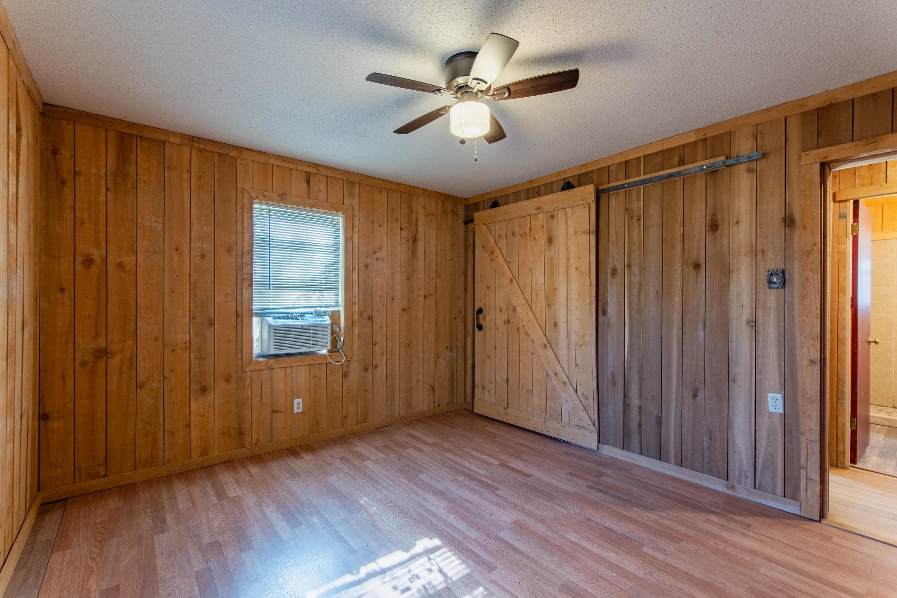 3001 Hamilton Road Ashland, MS 38603 - Photo 5 of 39 Unfurnished bedroom featuring ceiling fan, cooling unit, wooden walls, and light hardwood / wood-style flooring