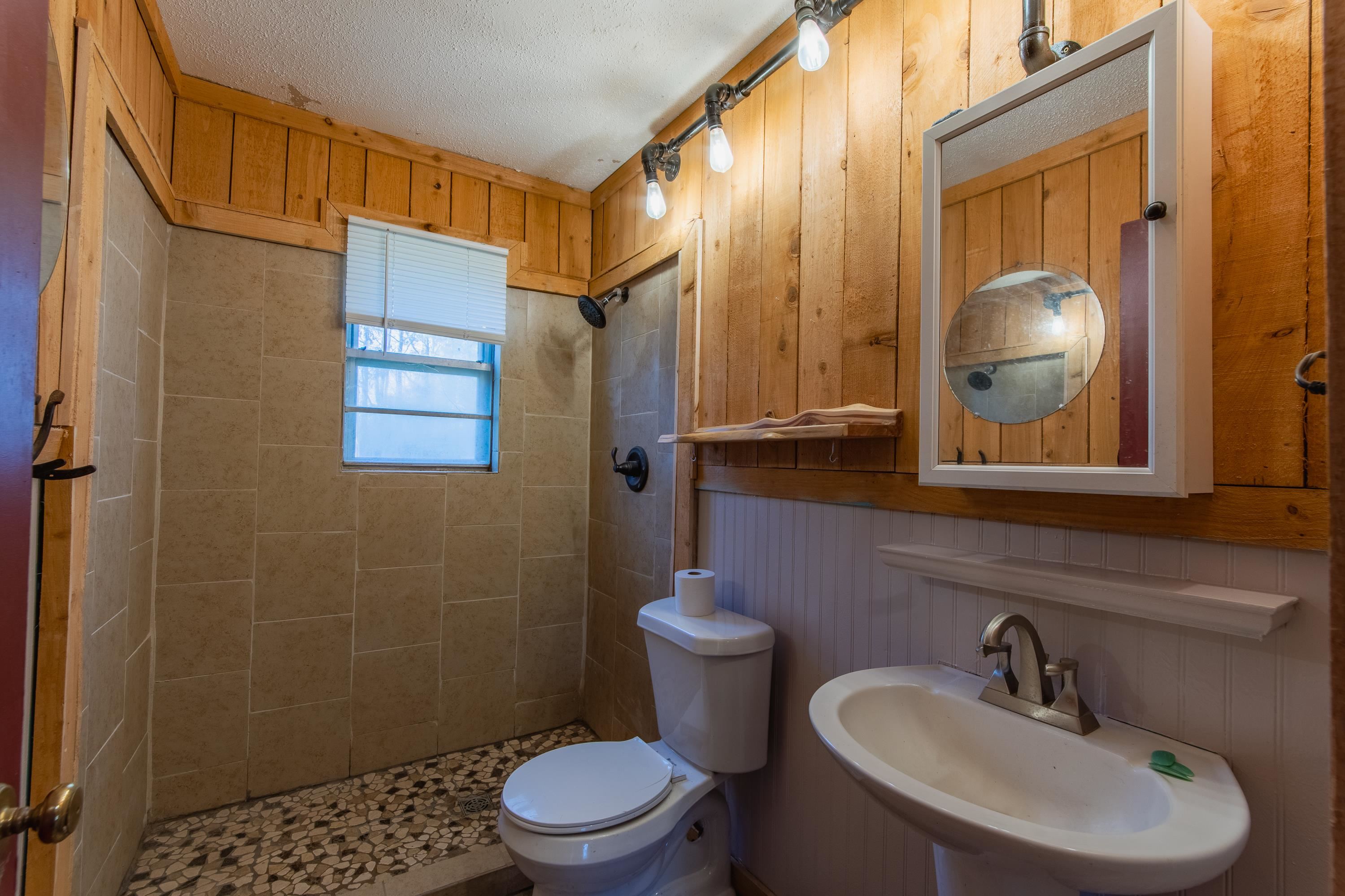 3001 Hamilton Road Ashland, MS 38603 - Photo 7 of 39 Bathroom with a tile shower, sink, wood walls, a textured ceiling, and toilet