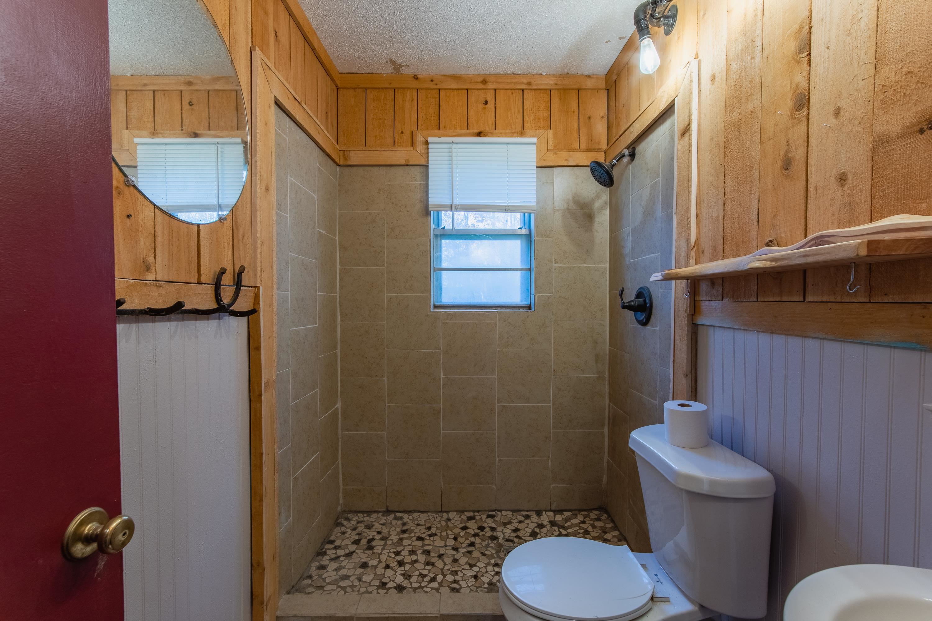 3001 Hamilton Road Ashland, MS 38603 - Photo 8 of 39 Bathroom featuring wood walls, tile patterned floors, toilet, a textured ceiling, and a tile shower