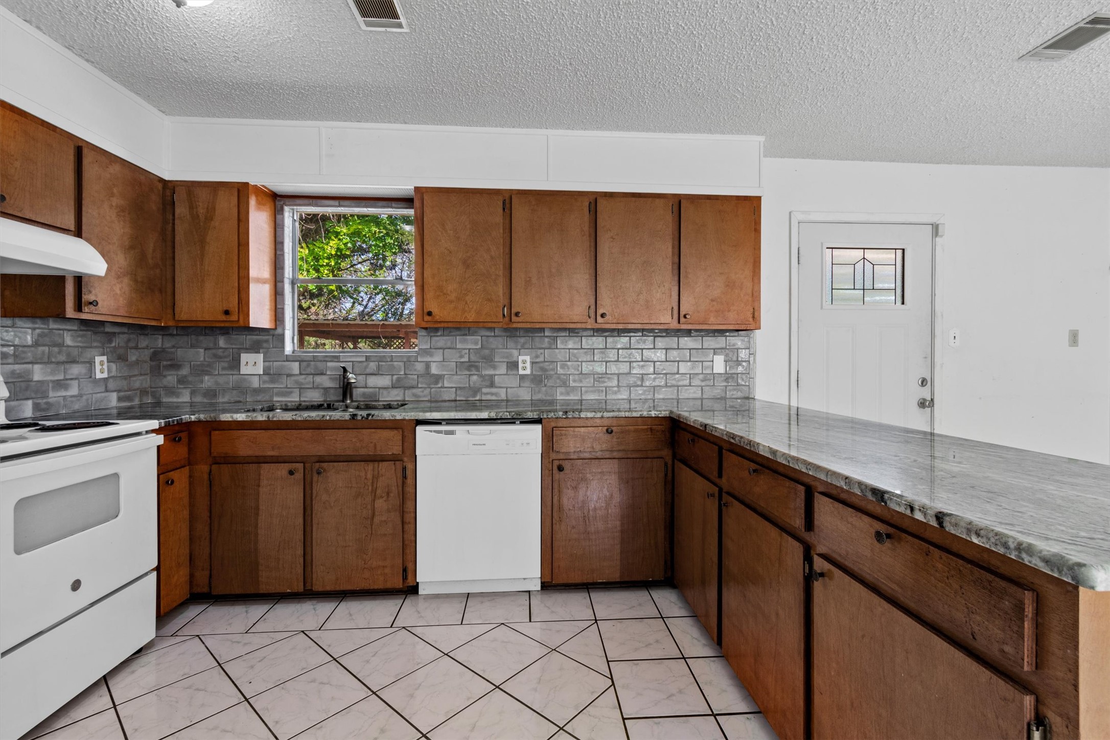 6 El Sol Road Wimberley, TX 78676 - Photo 4 of 20 Well-equipped kitchen with abundant wooden cabinetry, stylish countertops, and practical tile flooring.
