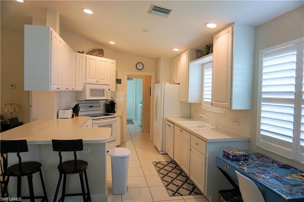 4194 St George Lane Naples, FL 34119 - Photo 9 of 29 a kitchen with stainless steel appliances granite countertop a stove top oven a sink a refrigerator and white cabinets