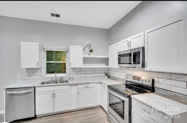 a kitchen with stainless steel appliances white cabinets and stove top oven